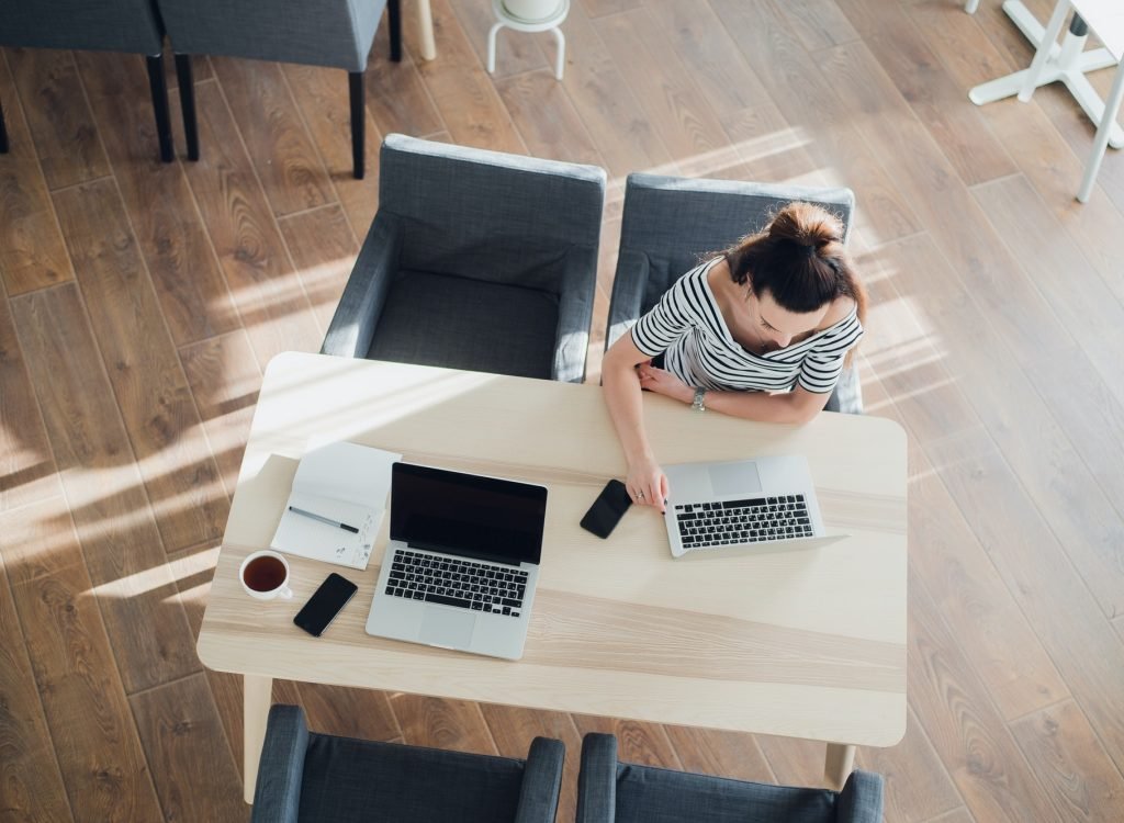 Top view of two women working at the same table in a cafe with laptops and smatphones.