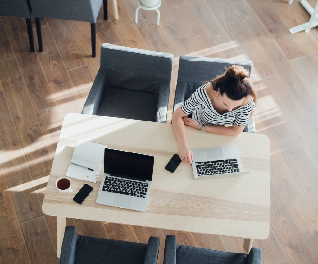 Top view of two women working at the same table in a cafe with laptops and smatphones.