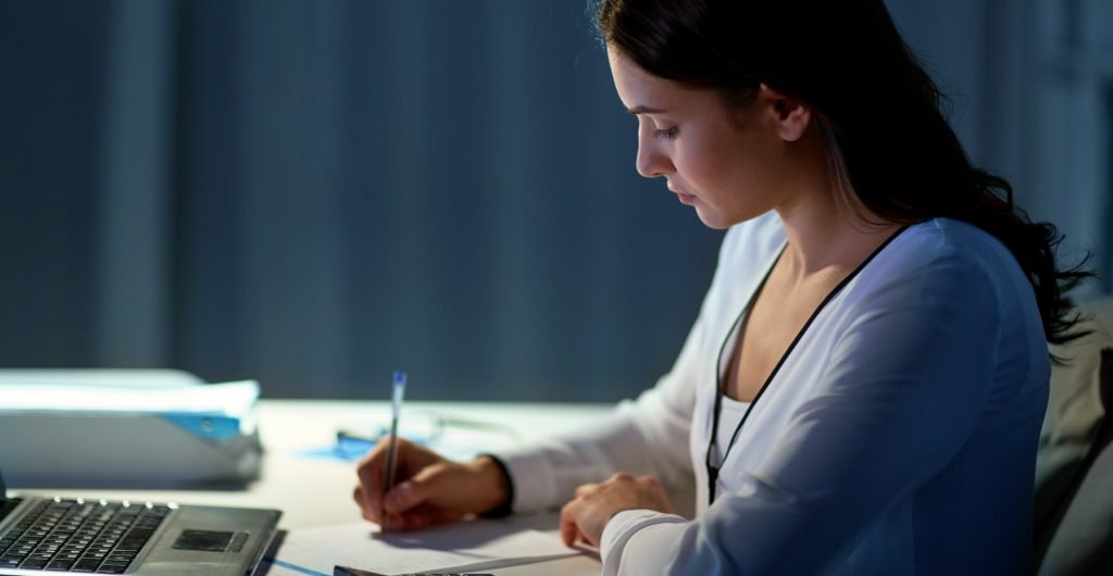 woman with calculator and papers at night office